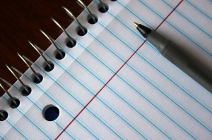 closeup of lined notebook with pen on top