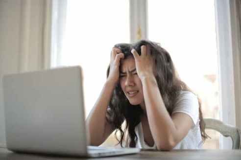 Image of a woman looking at a laptop screen with an expression of confusion.