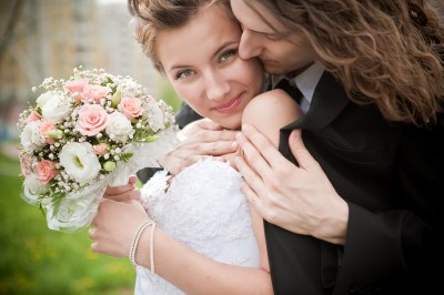 Close up of a new bridge and groom, groom hugging bridge, bridge holding bouquet of flowers