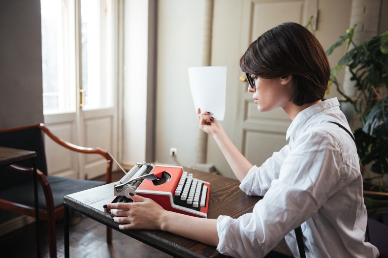 Side view of authoress with paper and typewriter